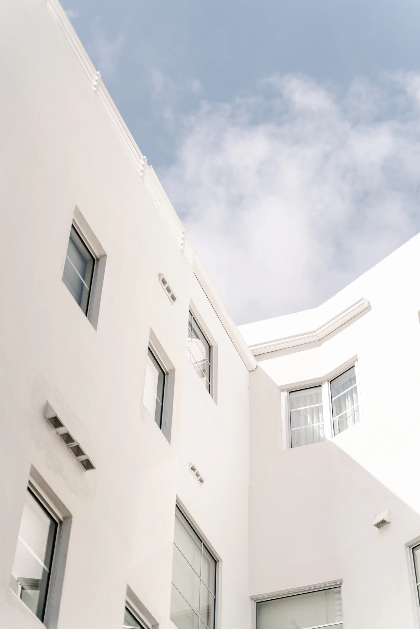 Soft light falls across a white building beneath an open blue sky