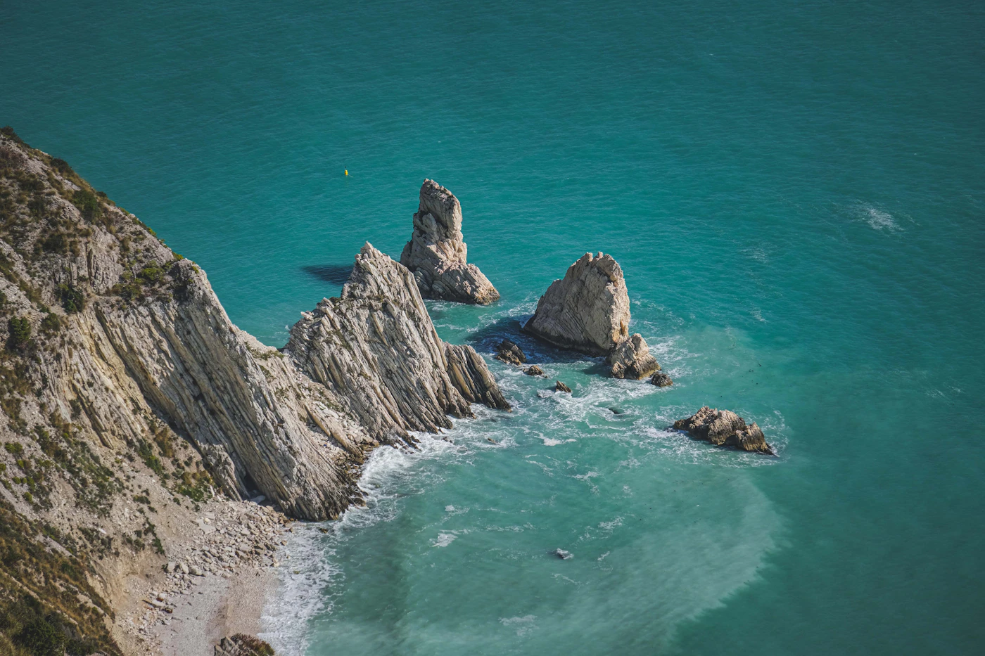 Clear blue coastal water meets pale, weathered rocks.