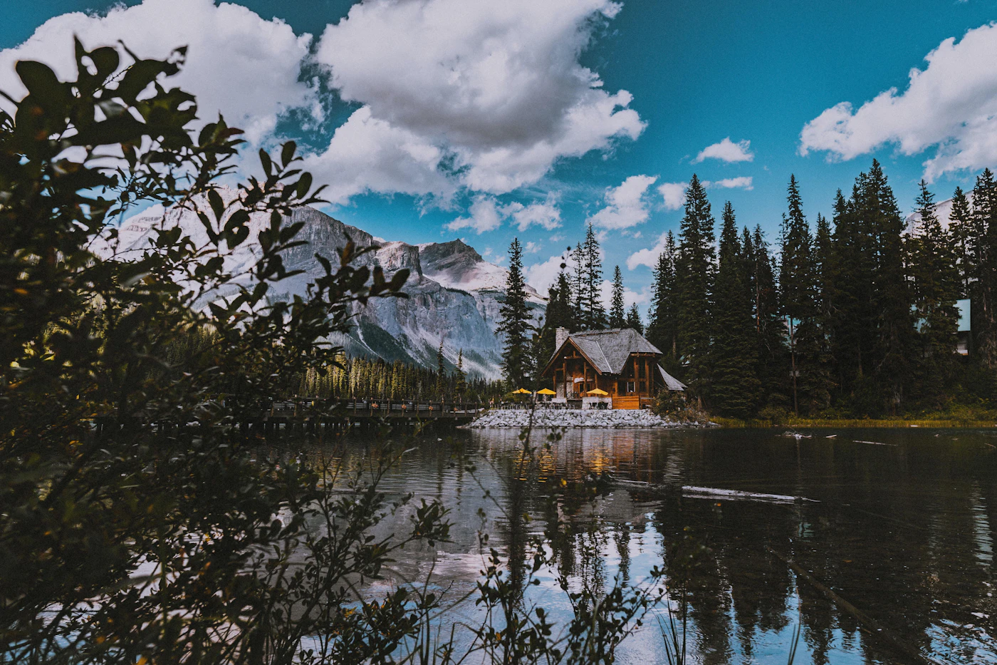 A timber lodge beside a still mountain lake, framed by pine trees