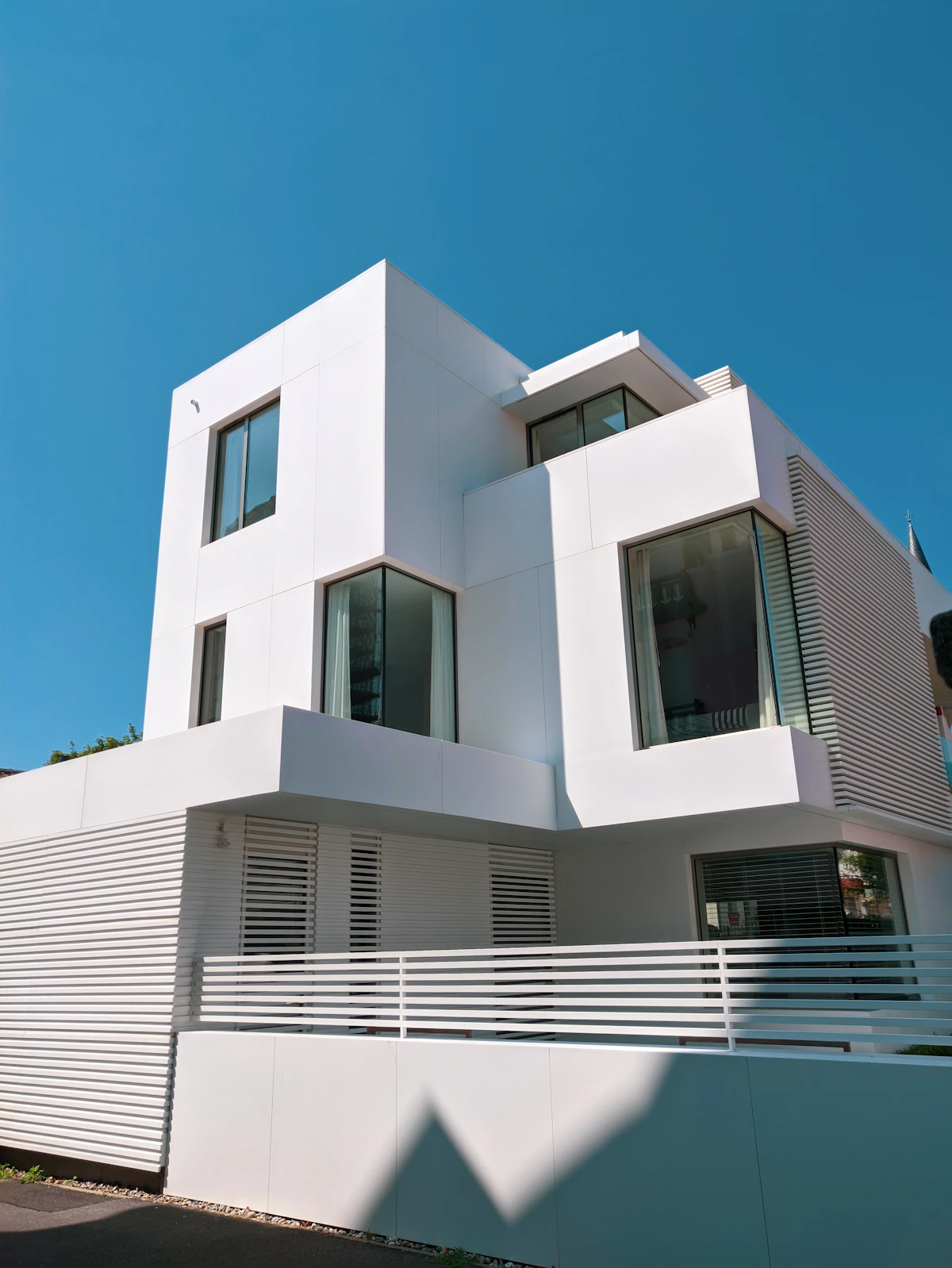 A white modern house with geometric balconies under a clear blue sky