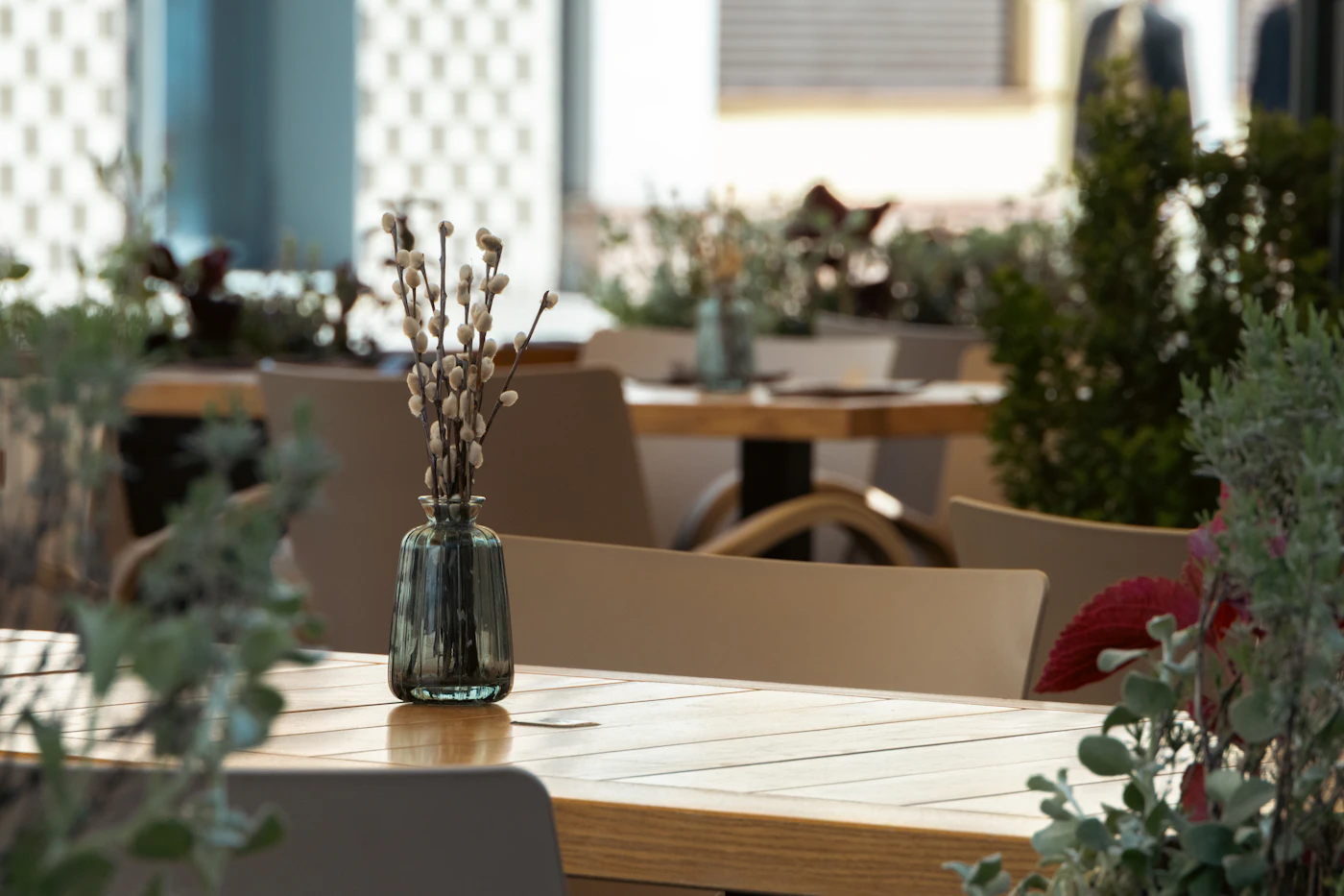 Sunlight falling across a wooden restaurant table with a small glass vase
