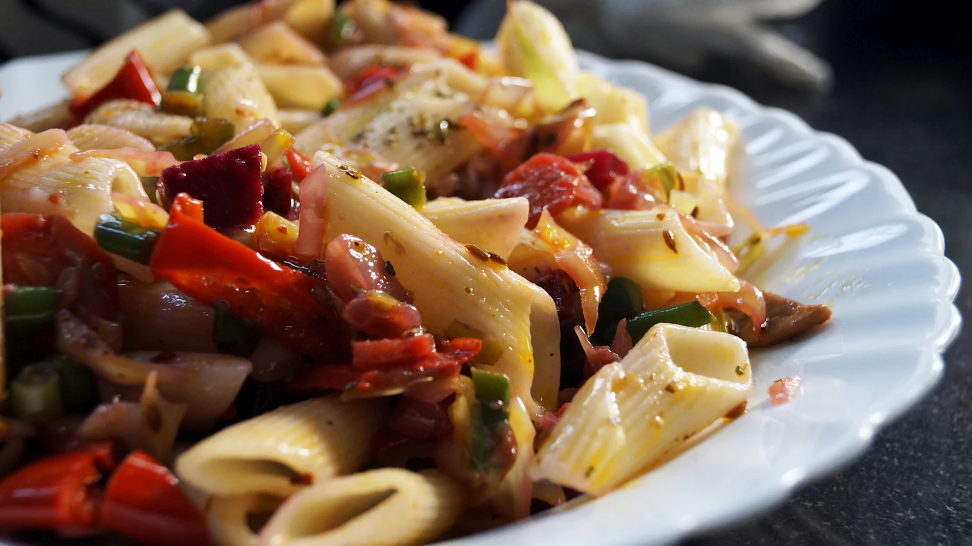 Penne pasta with peppers and herbs on a white plate